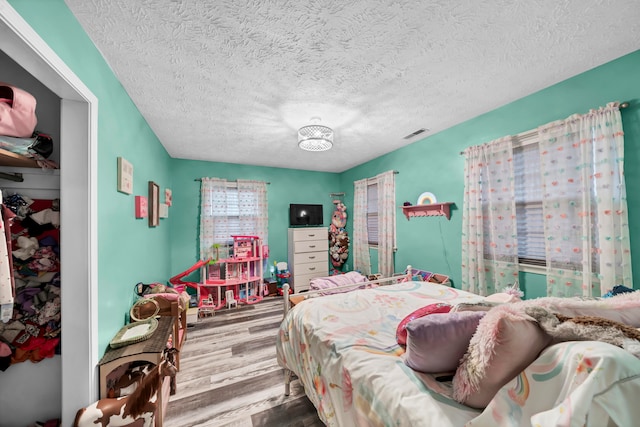 bedroom featuring a textured ceiling, wood-type flooring, and a closet