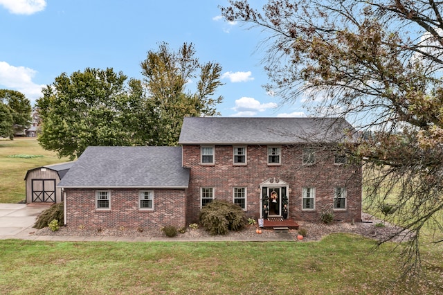 colonial-style house featuring a storage shed and a front lawn