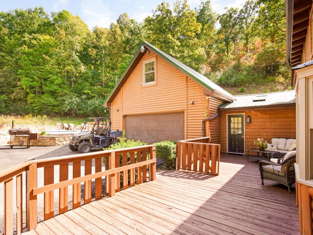 wooden deck with a garage and an outdoor fire pit