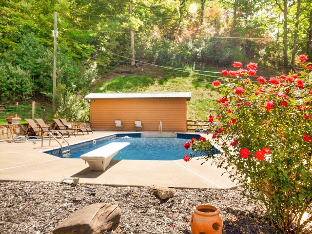 view of swimming pool with a diving board and a patio area