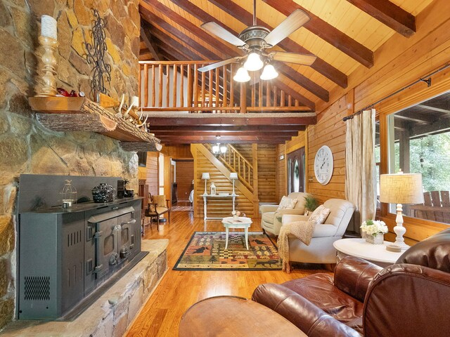 living room featuring ceiling fan, beam ceiling, wood-type flooring, wooden walls, and high vaulted ceiling