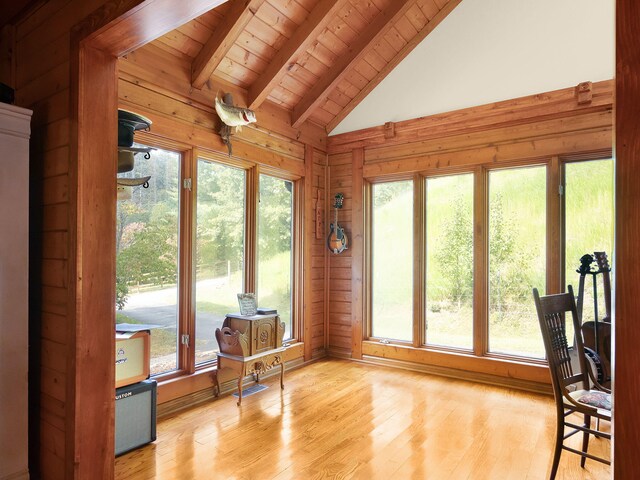 interior space featuring light wood-type flooring, vaulted ceiling with beams, and a wealth of natural light