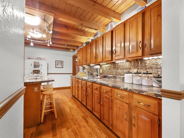 kitchen with beam ceiling, tasteful backsplash, a breakfast bar, wooden ceiling, and light hardwood / wood-style floors