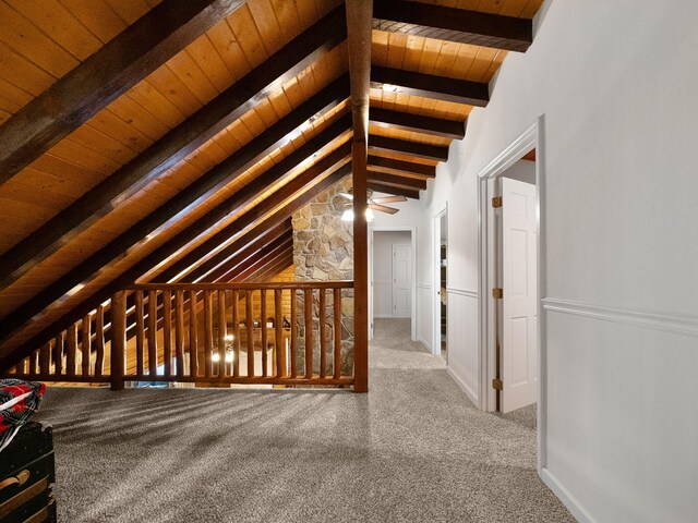 interior space with beam ceiling, carpet flooring, and wooden ceiling