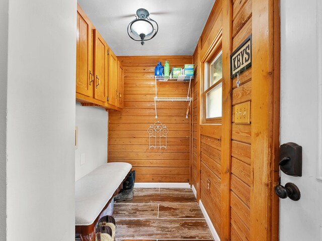 mudroom with wood walls and dark wood-type flooring