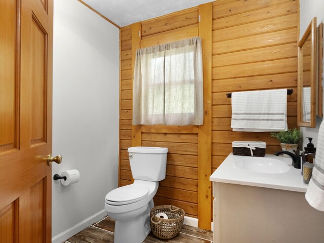 bathroom with wood-type flooring, vanity, wooden walls, and toilet