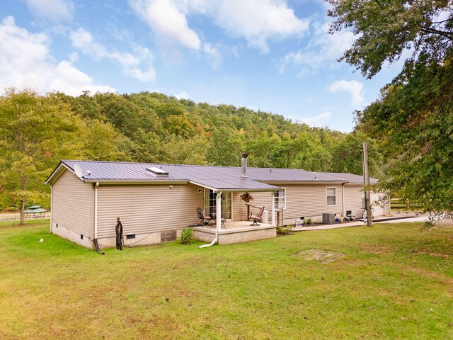 rear view of property with a patio, central air condition unit, and a yard