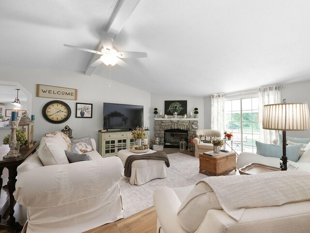 living room with ceiling fan, a fireplace, lofted ceiling with beams, and hardwood / wood-style floors