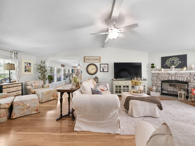 living room with a wealth of natural light, ceiling fan, light wood-type flooring, and a fireplace