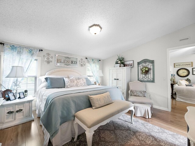 bedroom featuring a textured ceiling, hardwood / wood-style floors, and vaulted ceiling