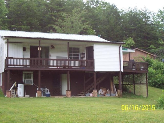 back of house featuring metal roof, stairs, a deck, and a lawn