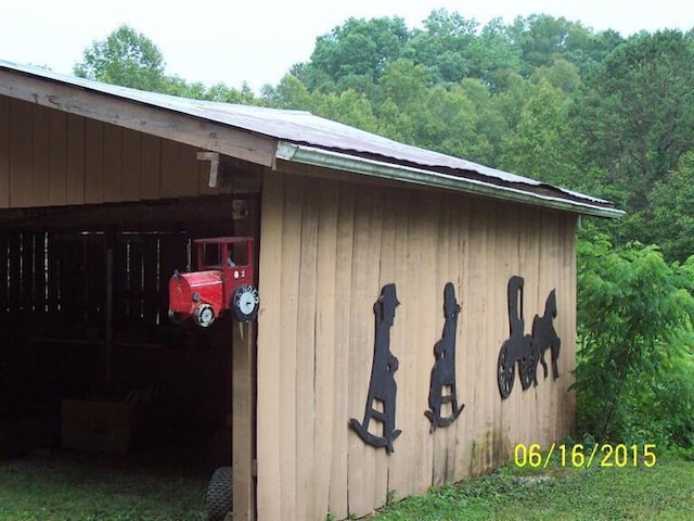 view of outdoor structure with a carport, an outdoor structure, and a view of trees