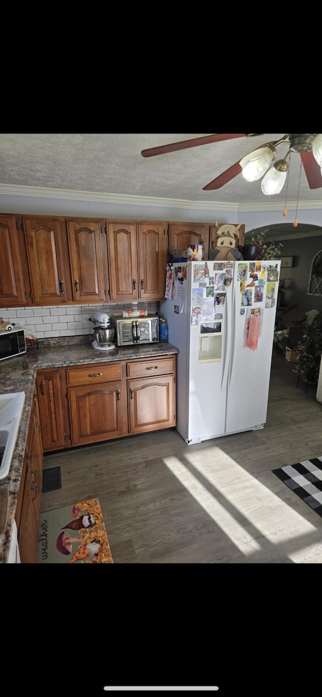 kitchen featuring brown cabinets, light wood-type flooring, white fridge with ice dispenser, and a sink