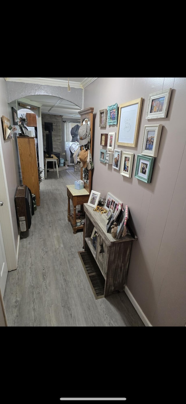 hallway featuring decorative columns, crown molding, and wood finished floors
