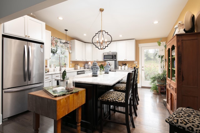 kitchen with stainless steel appliances, a kitchen island, plenty of natural light, and white cabinetry