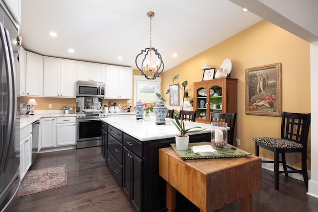 kitchen featuring appliances with stainless steel finishes, white cabinets, a center island, dark hardwood / wood-style floors, and hanging light fixtures