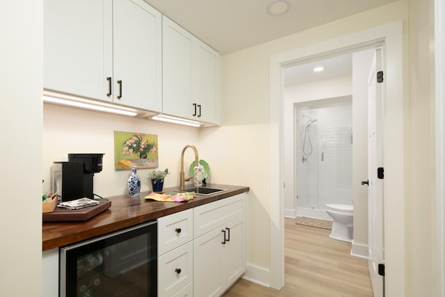 bar with white cabinets, sink, beverage cooler, and wooden counters