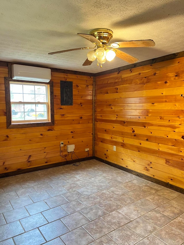 unfurnished room featuring an AC wall unit, a textured ceiling, ceiling fan, wooden walls, and electric panel