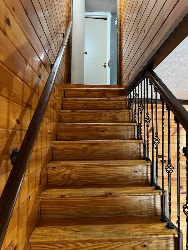 staircase with wood-type flooring and wood walls