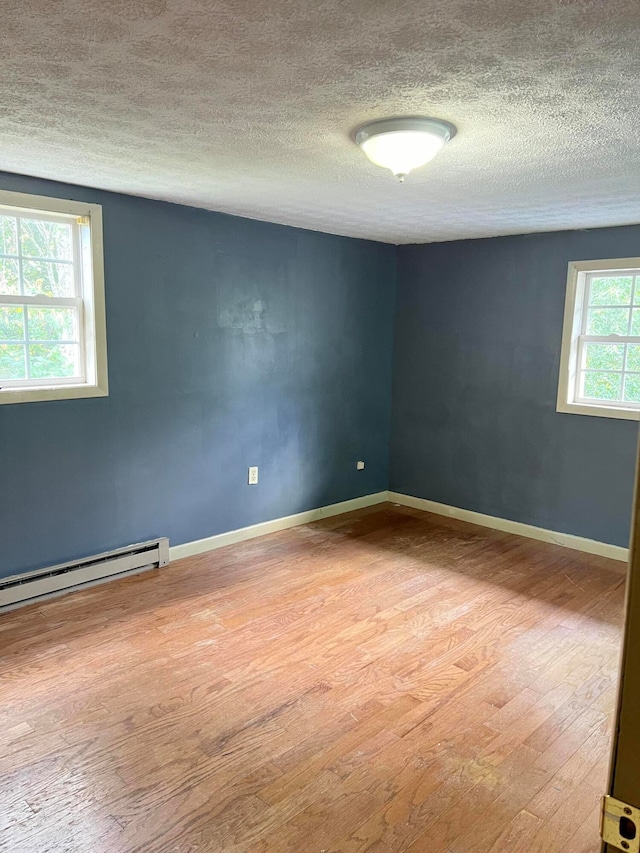 unfurnished room with a wealth of natural light, a textured ceiling, and light wood-type flooring