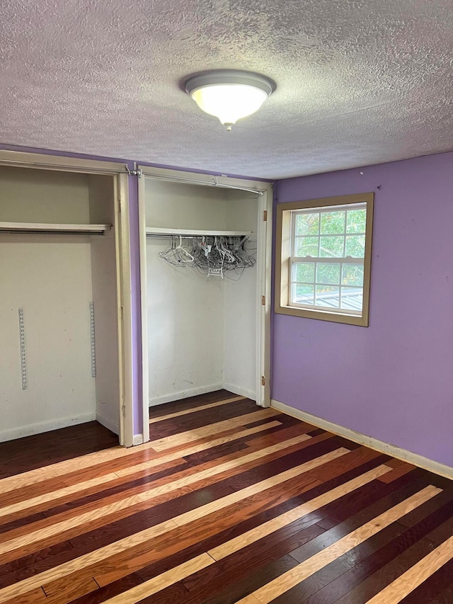 unfurnished bedroom featuring a textured ceiling and dark hardwood / wood-style floors