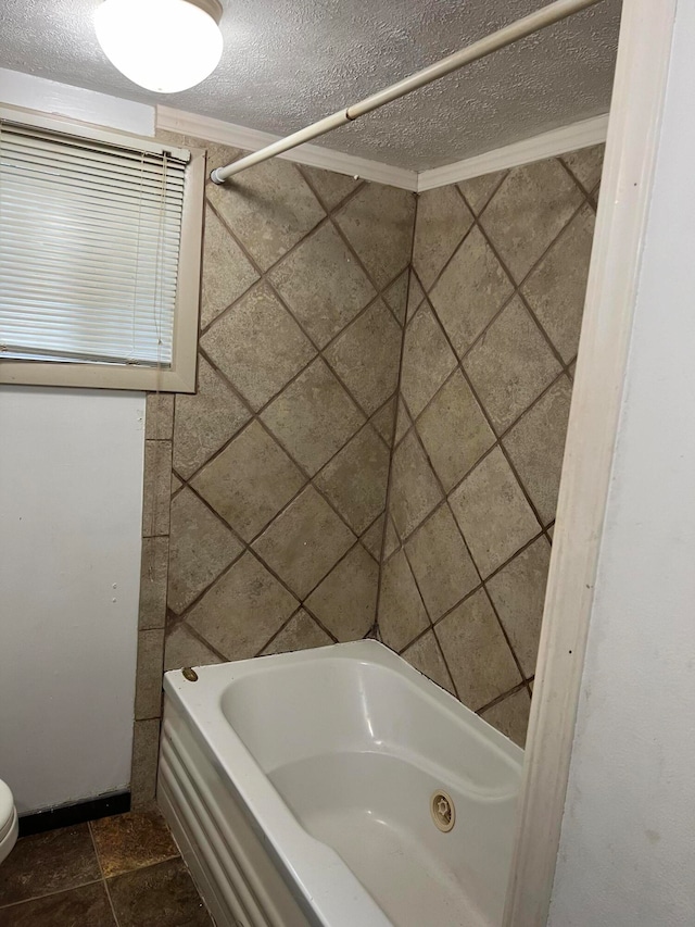 bathroom with a textured ceiling, crown molding, a bathing tub, and toilet