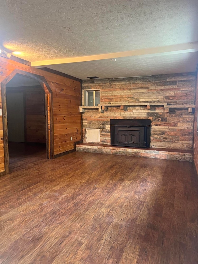 unfurnished living room featuring a textured ceiling, wooden walls, and hardwood / wood-style floors