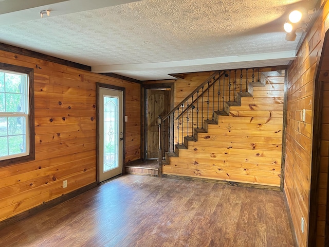 foyer entrance featuring a textured ceiling, wood walls, and dark hardwood / wood-style flooring