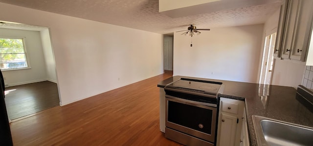 kitchen with wood-type flooring, a textured ceiling, stainless steel range with electric stovetop, and ceiling fan