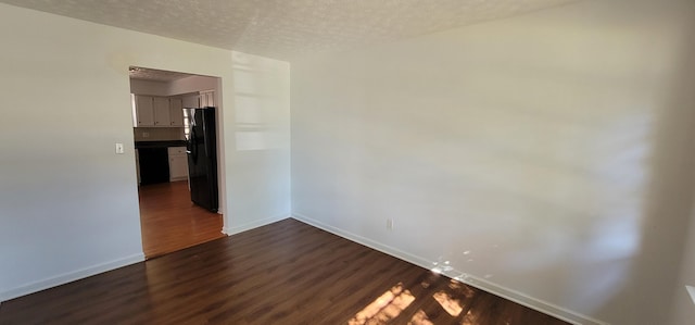 spare room with dark hardwood / wood-style floors and a textured ceiling