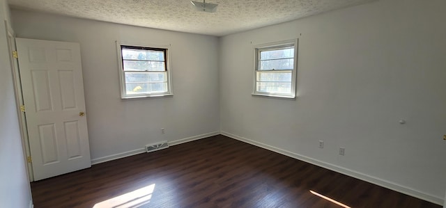 unfurnished room with a textured ceiling and dark hardwood / wood-style floors