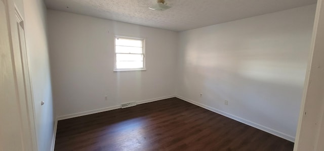 empty room with a textured ceiling and dark hardwood / wood-style floors