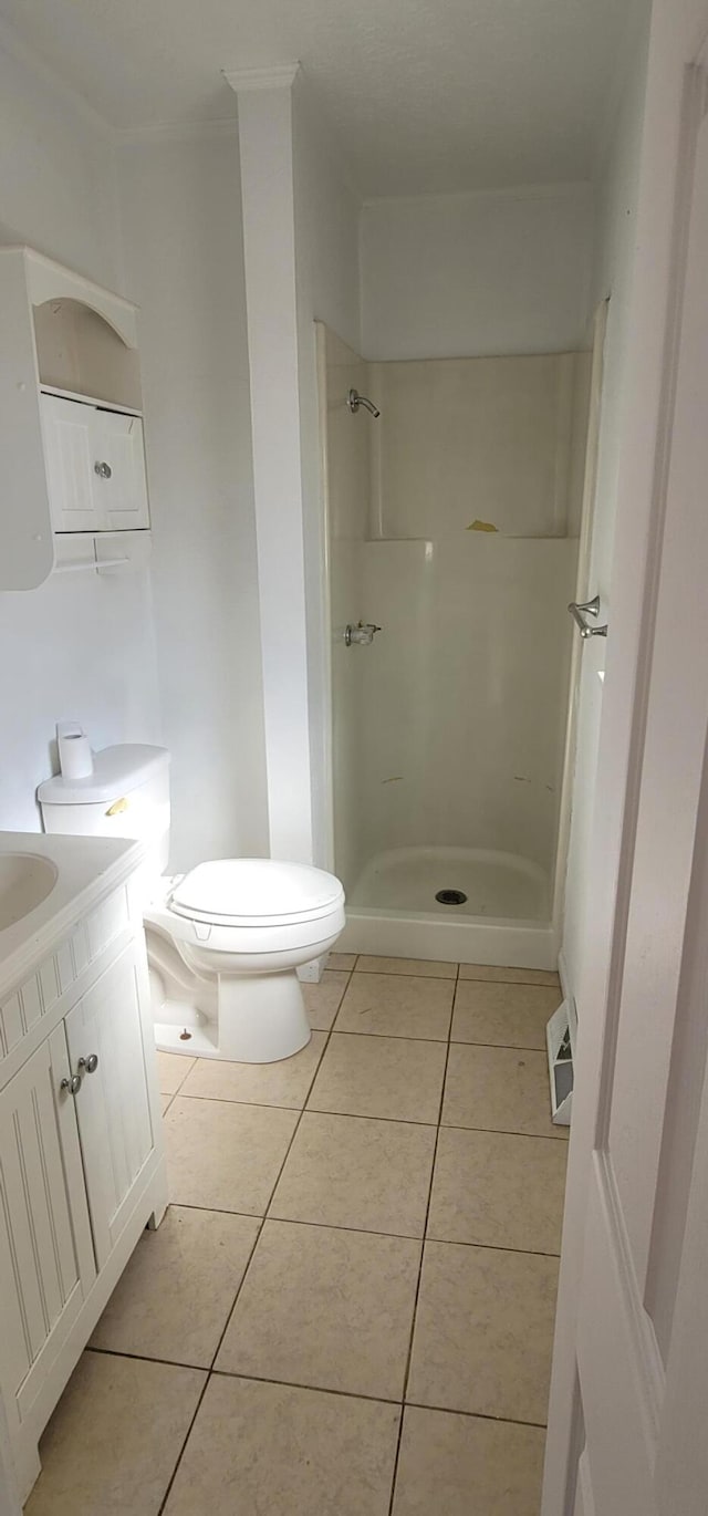 bathroom featuring tile patterned flooring, vanity, toilet, and a shower