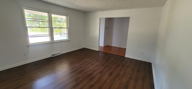 spare room with a textured ceiling and dark wood-type flooring