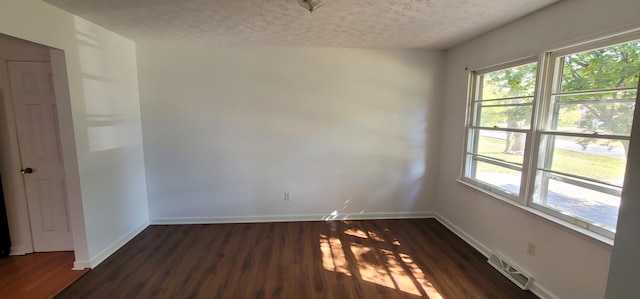 empty room with a textured ceiling and dark wood-type flooring