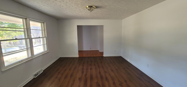 unfurnished room featuring a textured ceiling and dark wood-type flooring