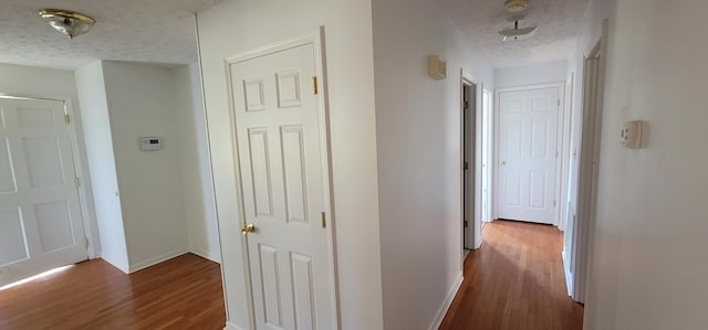 hall with dark hardwood / wood-style flooring and a textured ceiling