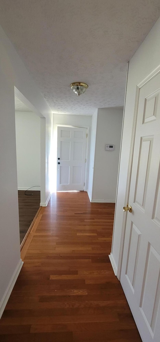 hallway featuring dark hardwood / wood-style floors and a textured ceiling