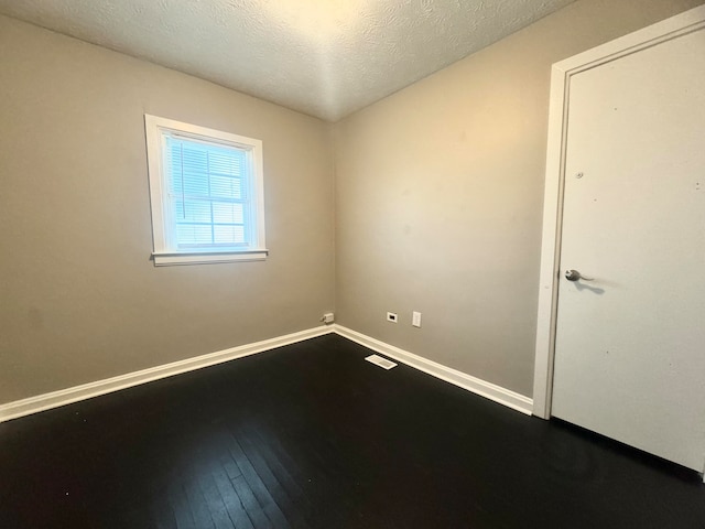 spare room with a textured ceiling and wood-type flooring