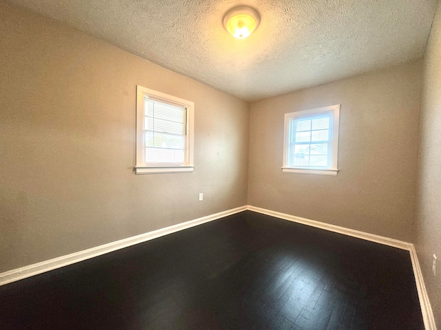 empty room featuring a textured ceiling and hardwood / wood-style floors