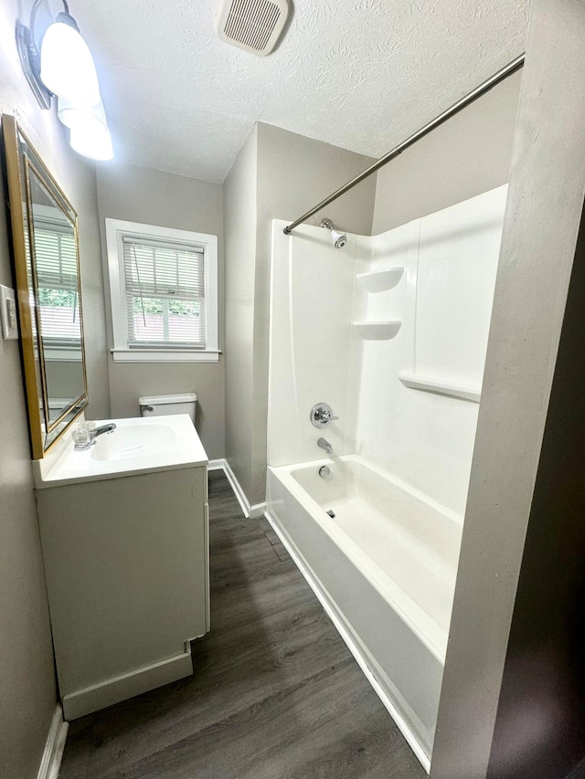 full bathroom with a textured ceiling, hardwood / wood-style floors, shower / bathing tub combination, vanity, and toilet