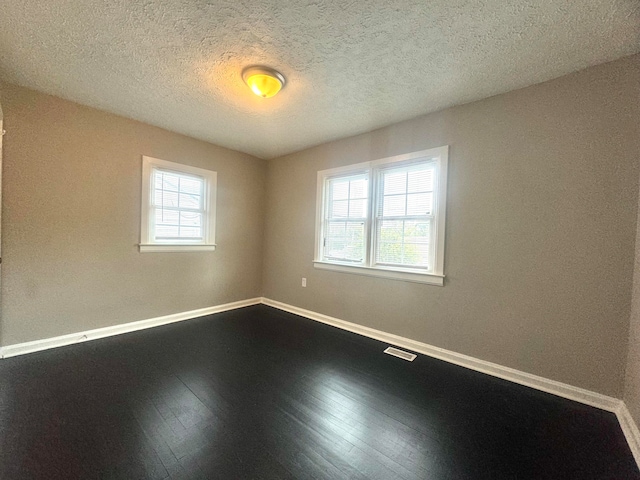 spare room featuring hardwood / wood-style flooring and a textured ceiling