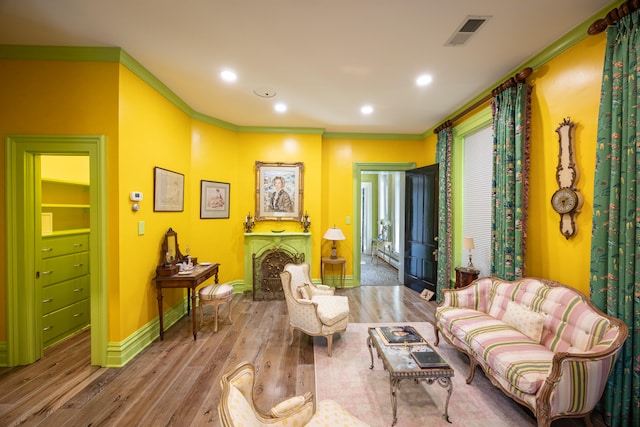 sitting room with light wood-type flooring and crown molding