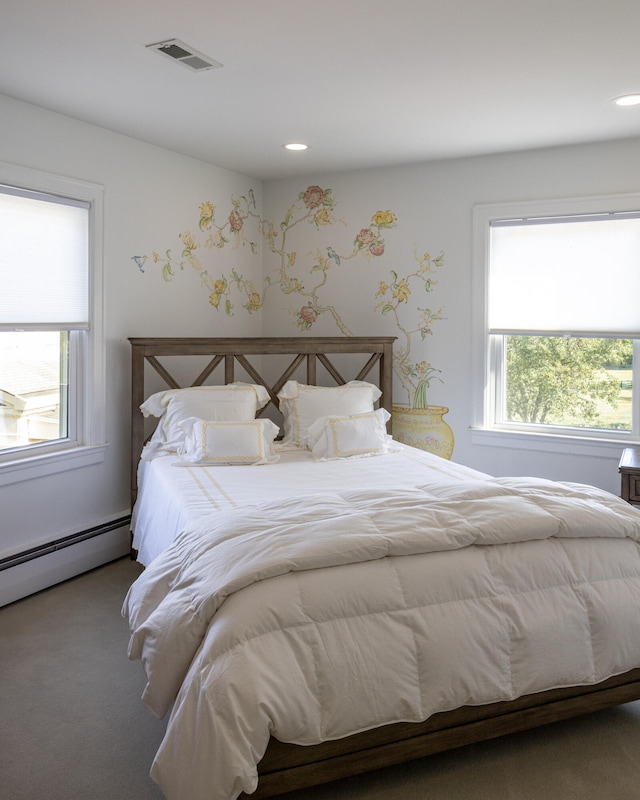 carpeted bedroom with baseboard heating and multiple windows