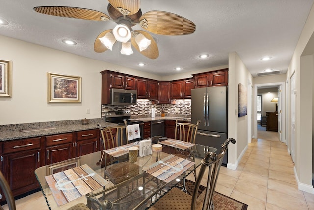 kitchen featuring ceiling fan, a textured ceiling, appliances with stainless steel finishes, dark stone counters, and decorative backsplash