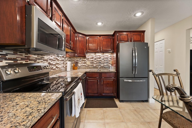 kitchen with light stone countertops, a textured ceiling, appliances with stainless steel finishes, and sink