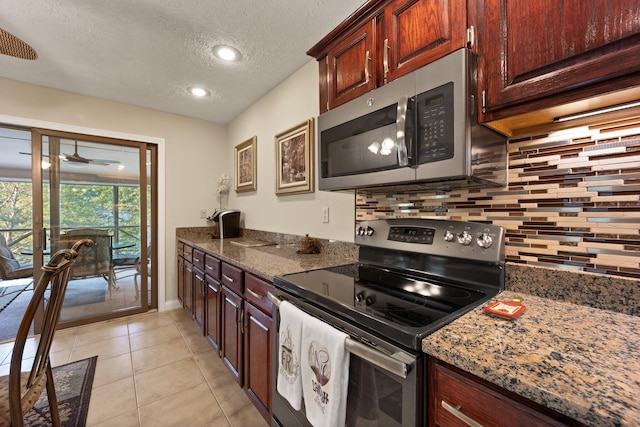 kitchen featuring a textured ceiling, tasteful backsplash, stainless steel appliances, light tile patterned floors, and dark stone countertops