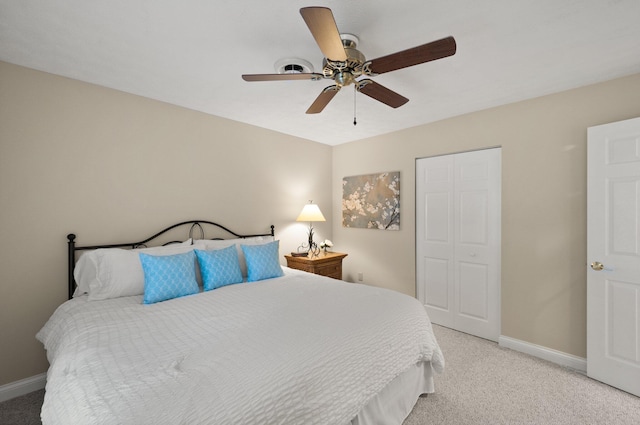 bedroom with ceiling fan, light colored carpet, and a closet