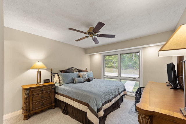 carpeted bedroom featuring ceiling fan and a textured ceiling