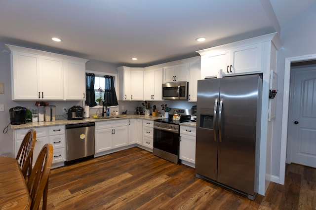 kitchen with stainless steel appliances, white cabinetry, sink, light stone counters, and dark hardwood / wood-style floors